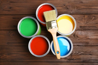 Flat lay composition with paint cans and brush on wooden background