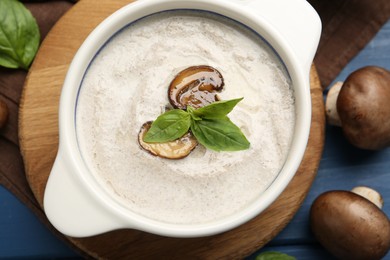 Fresh homemade mushroom soup in ceramic pot on blue wooden table