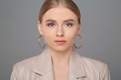 Photo of Beautiful young woman with elegant earrings on gray background