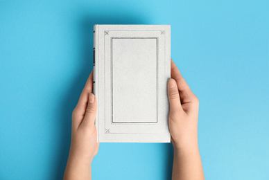 Woman with book on blue background, top view. Space for design