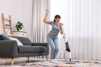 Happy young housewife having fun while cleaning at home