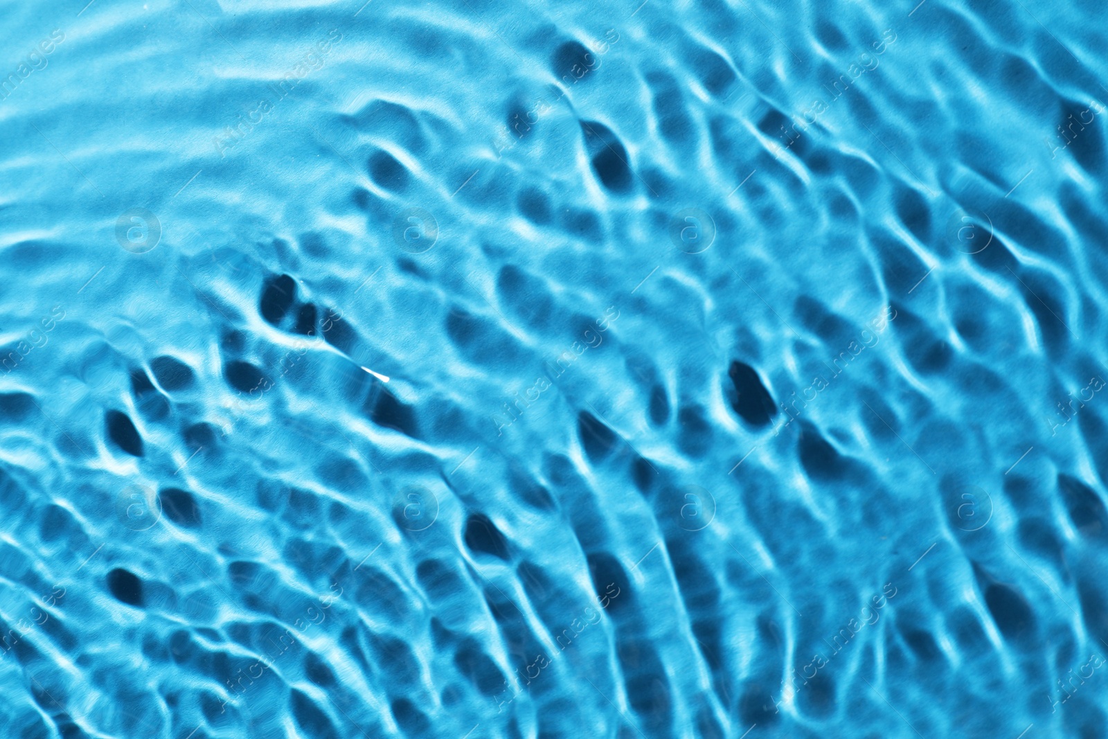 Image of Rippled surface of clear water on light blue background, closeup