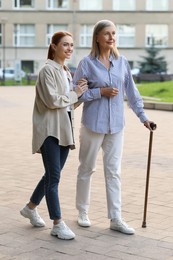 Photo of Senior lady with walking cane and young woman outdoors