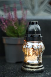 Photo of Grave light and potted heather on granite surface at cemetery, closeup