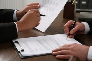 Photo of Law and justice. Lawyers working with documents at wooden table, closeup