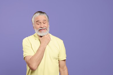 Photo of Senior man suffering from sore throat on light purple background, space for text. Cold symptoms