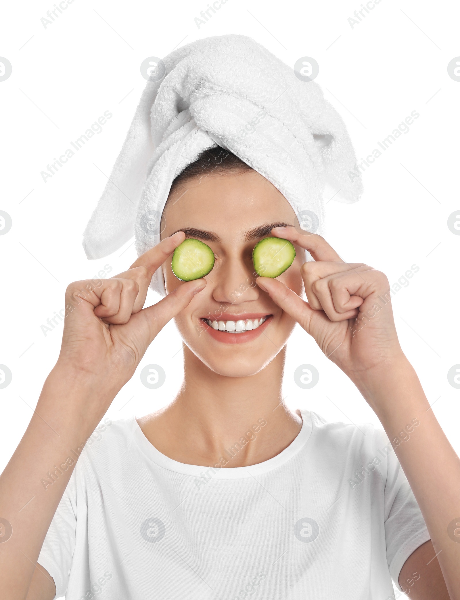 Photo of Happy young woman with towel holding cucumber slices on white background. Organic face mask