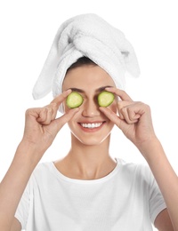 Happy young woman with towel holding cucumber slices on white background. Organic face mask