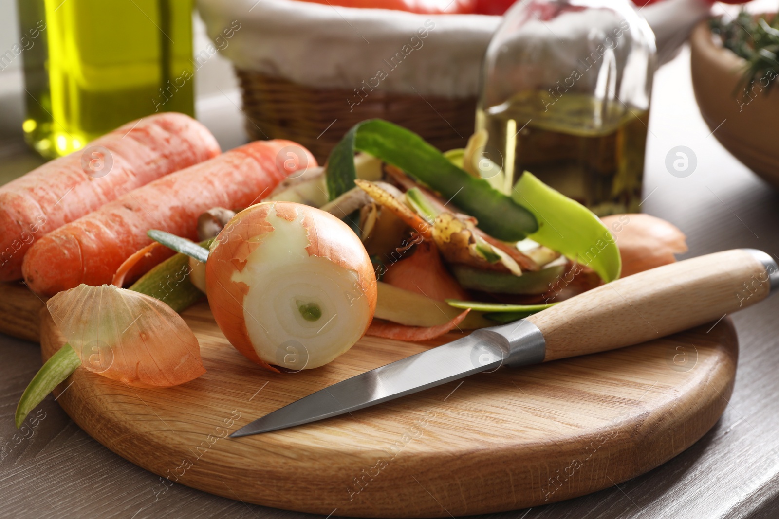 Photo of Peels of fresh vegetables and knife on wooden table, closeup