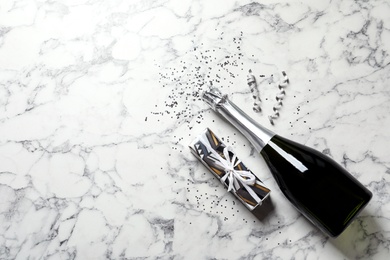 Photo of Flat lay composition with bottle of champagne for celebration on white marble background. Space for text