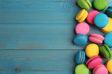 Photo of Delicious colorful macarons on light blue wooden table, flat lay. Space for text