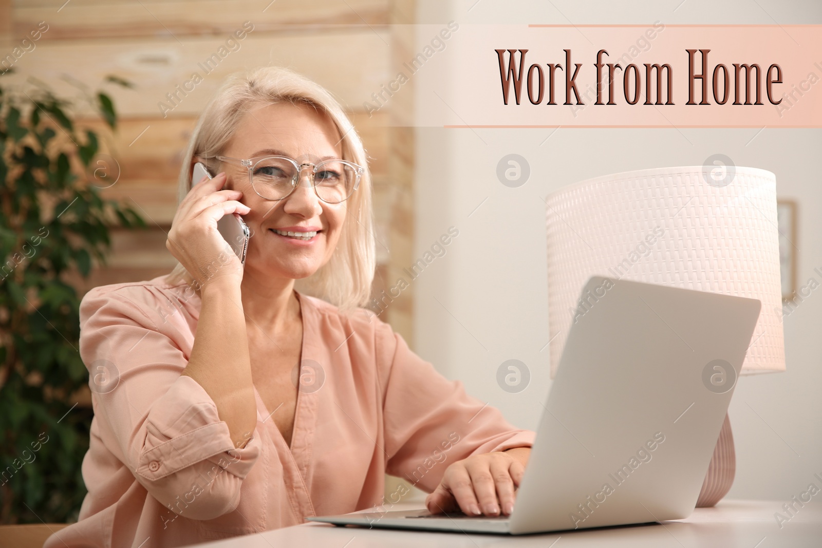 Image of Beautiful mature woman with laptop talking on smartphone in room. Work from home