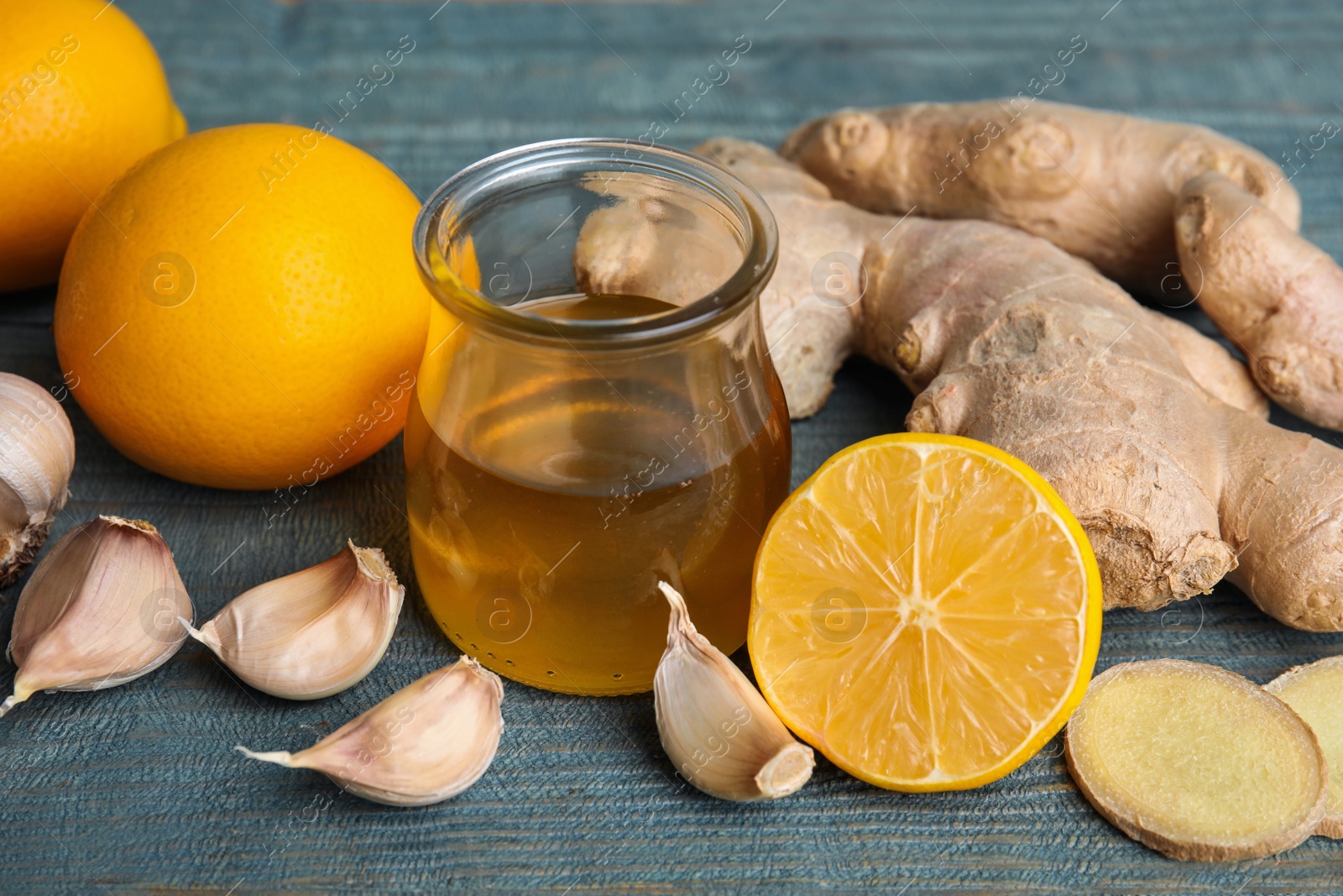 Photo of Fresh garlic and other natural cold remedies on light blue wooden table