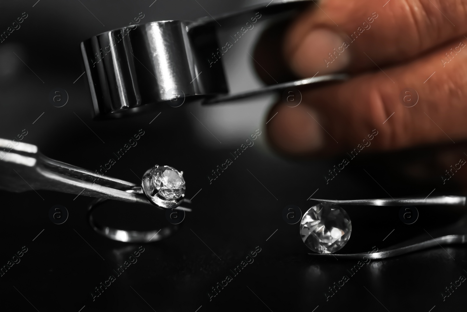 Photo of Professional jeweler working with beautiful ring at table, closeup