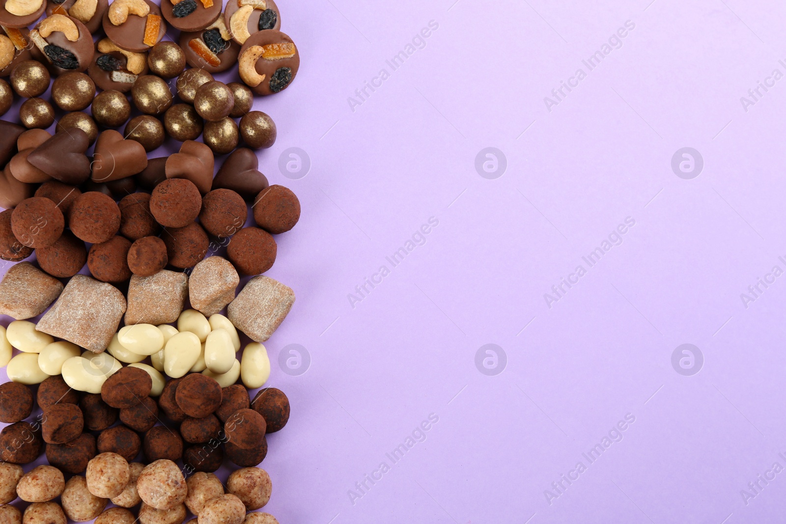 Photo of Different delicious chocolate candies on lilac background, flat lay. Space for text