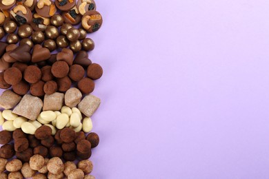 Different delicious chocolate candies on lilac background, flat lay. Space for text