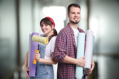 Couple with wallpaper rolls and roller on blurred background