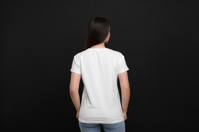 Photo of Woman wearing white t-shirt on black background, back view