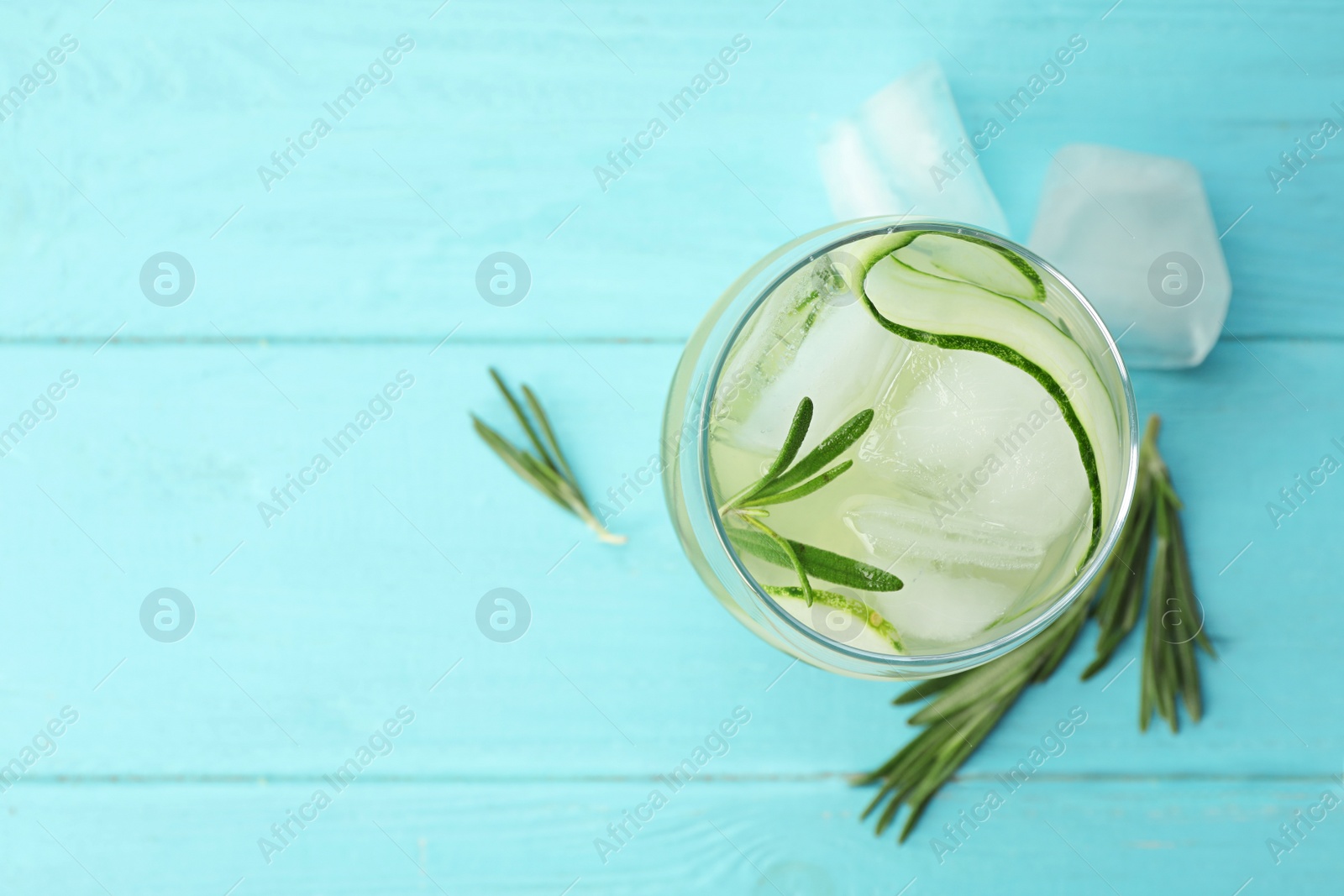 Photo of Glass of cucumber lemonade on light blue wooden table, top view and space for text. Summer drink