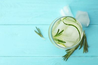 Glass of cucumber lemonade on light blue wooden table, top view and space for text. Summer drink