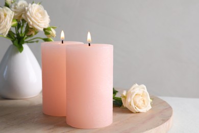 Photo of Burning candles and beautiful roses on white table