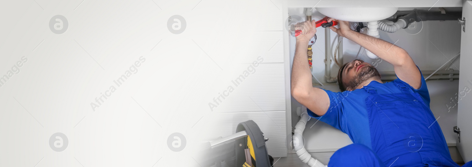 Image of Professional plumber in uniform fixing sink with pipe wrench space for text. Banner design