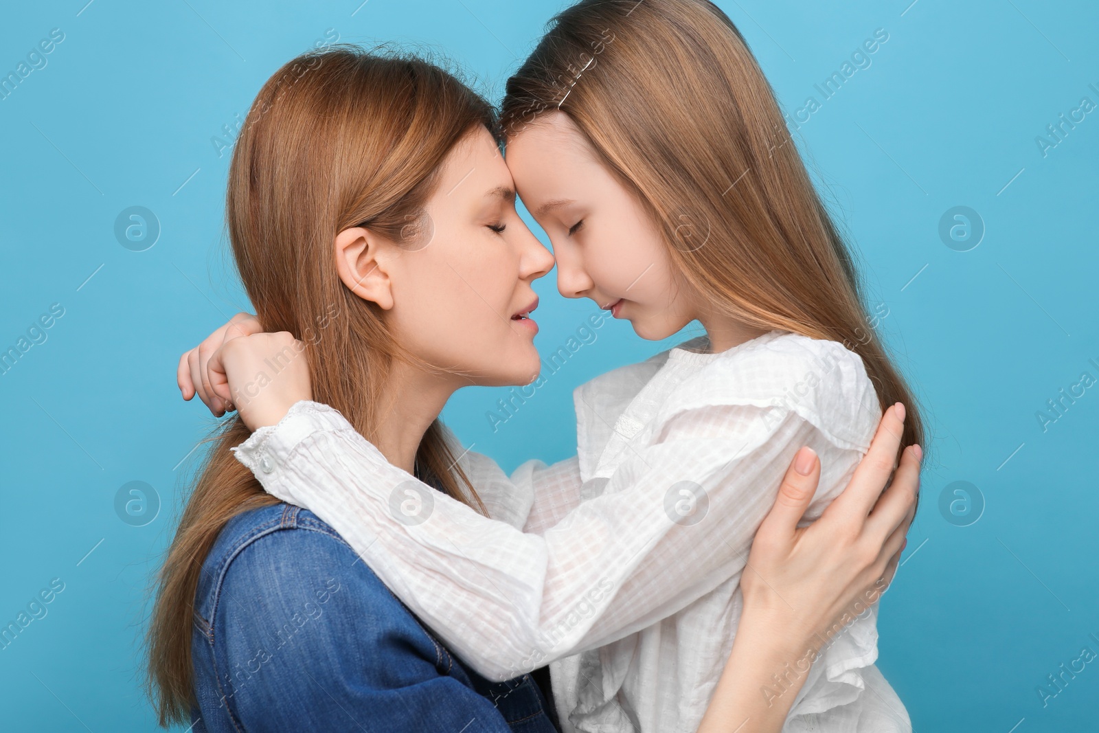 Photo of Portrait of mother and her cute daughter on light blue background