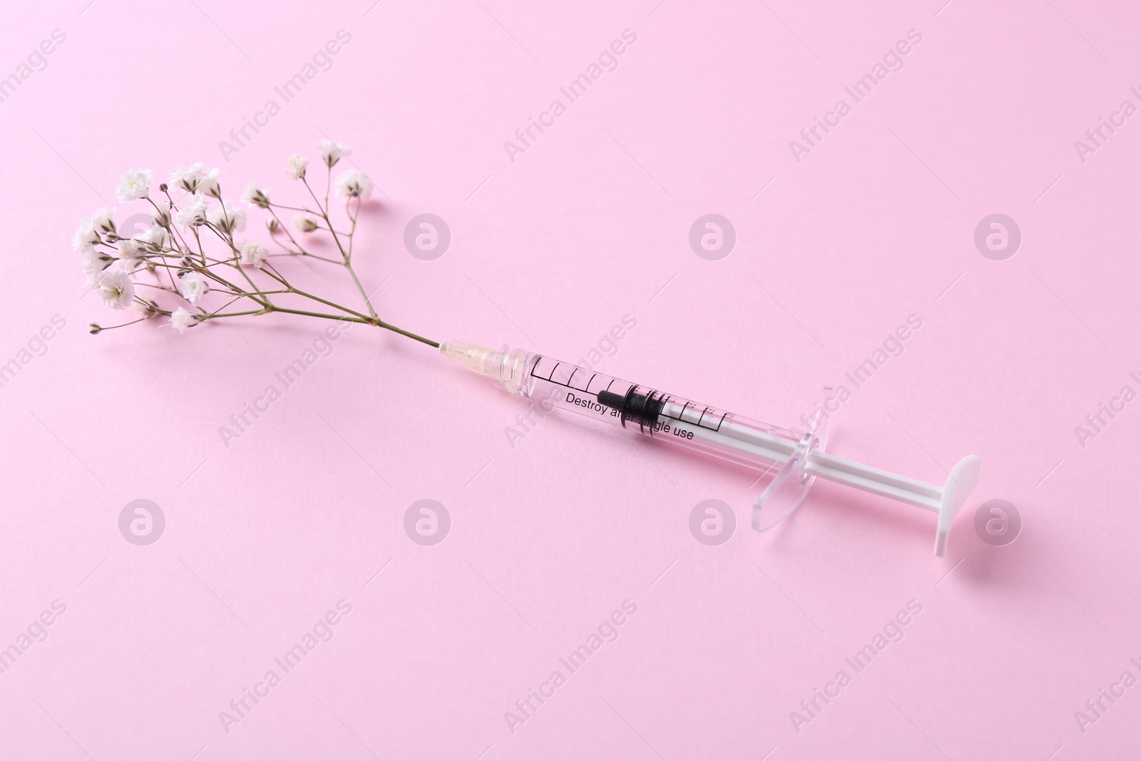 Photo of Cosmetology. Medical syringe and gypsophila on pink background