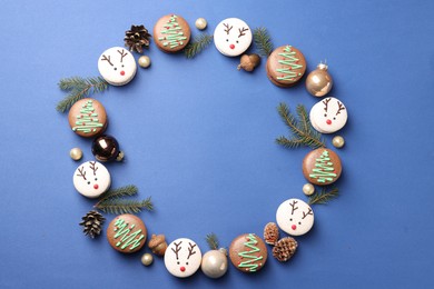 Photo of Frame of beautifully decorated Christmas macarons on blue background, flat lay. Space for text