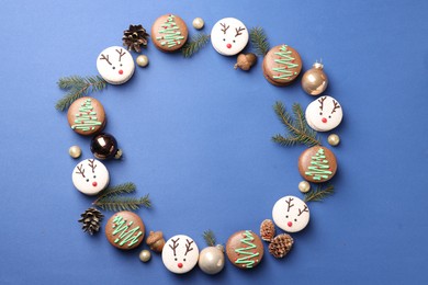 Frame of beautifully decorated Christmas macarons on blue background, flat lay. Space for text