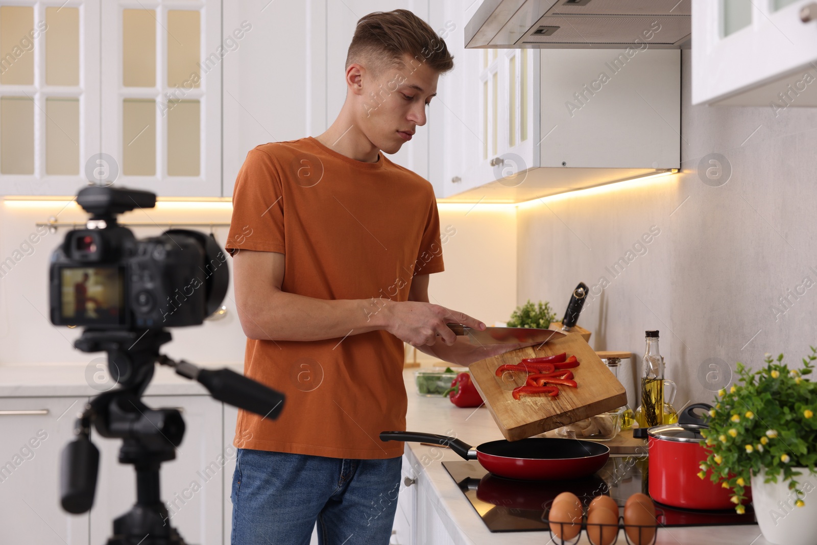 Photo of Food blogger cooking while recording video in kitchen