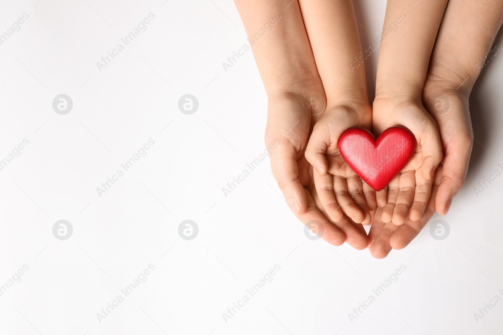 Photo of Woman and kid holding red heart in hands on white background, top view