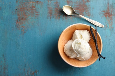 Photo of Bowl with tasty vanilla ice cream on wooden background