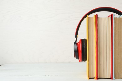 Photo of Books and modern headphones on white wooden table. Space for text