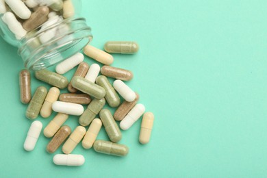 Photo of Vitamin pills and bottle on mint color background, top view. Space for text