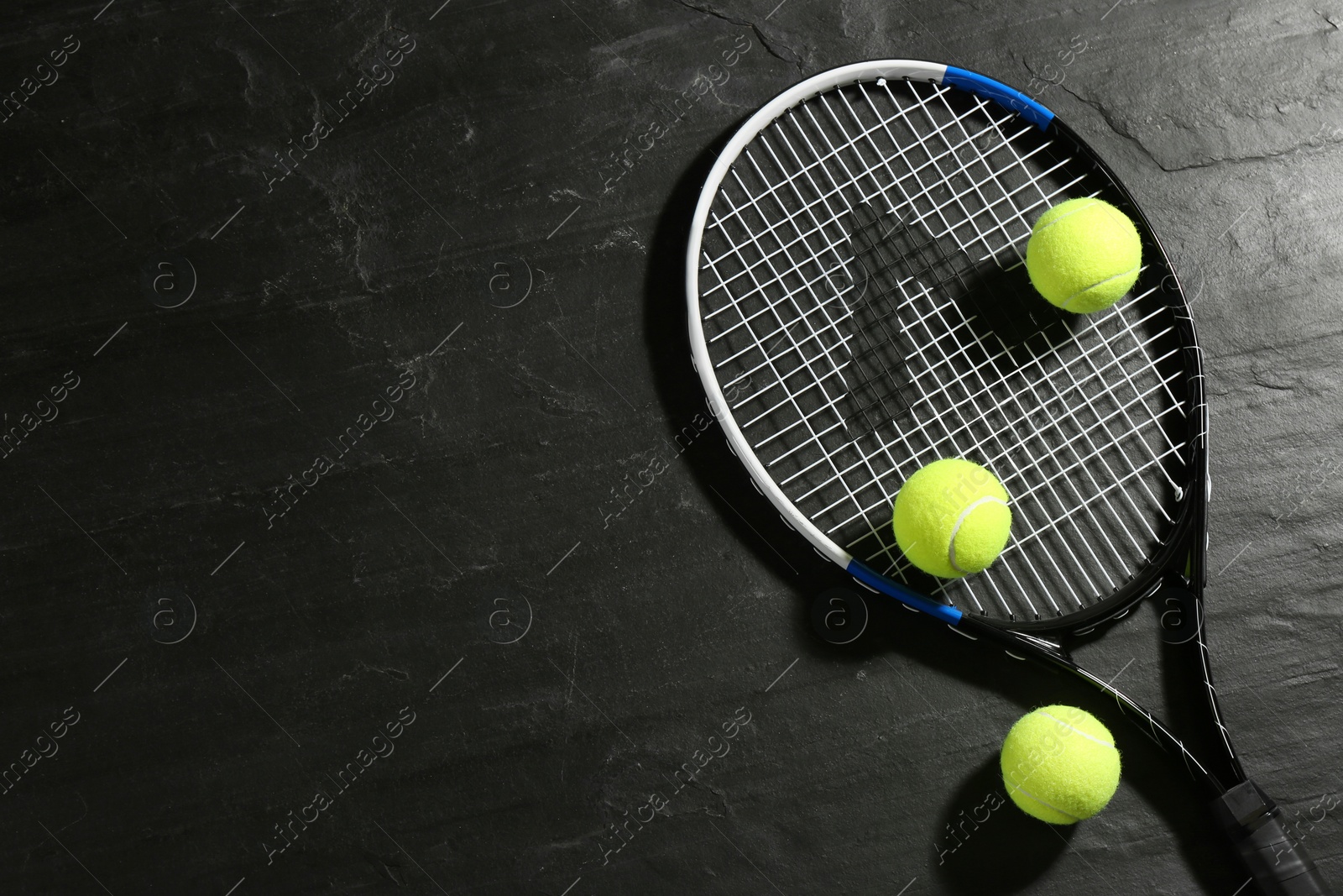 Photo of Tennis racket and balls on black table, flat lay. Sports equipment