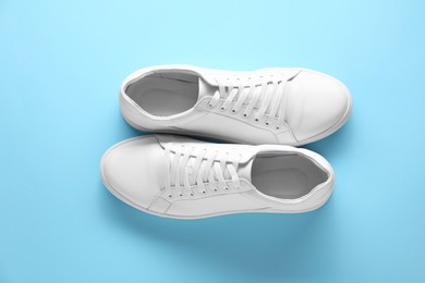 Photo of Pair of stylish white sneakers on light blue background, top view