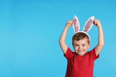 Photo of Portrait of little boy in Easter bunny ears headband on color background, space for text