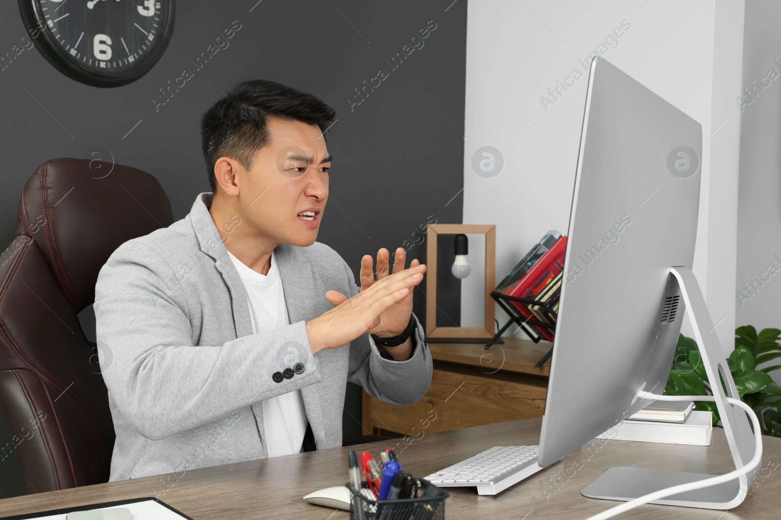 Photo of Emotional boss having online meeting via computer at wooden table in modern office