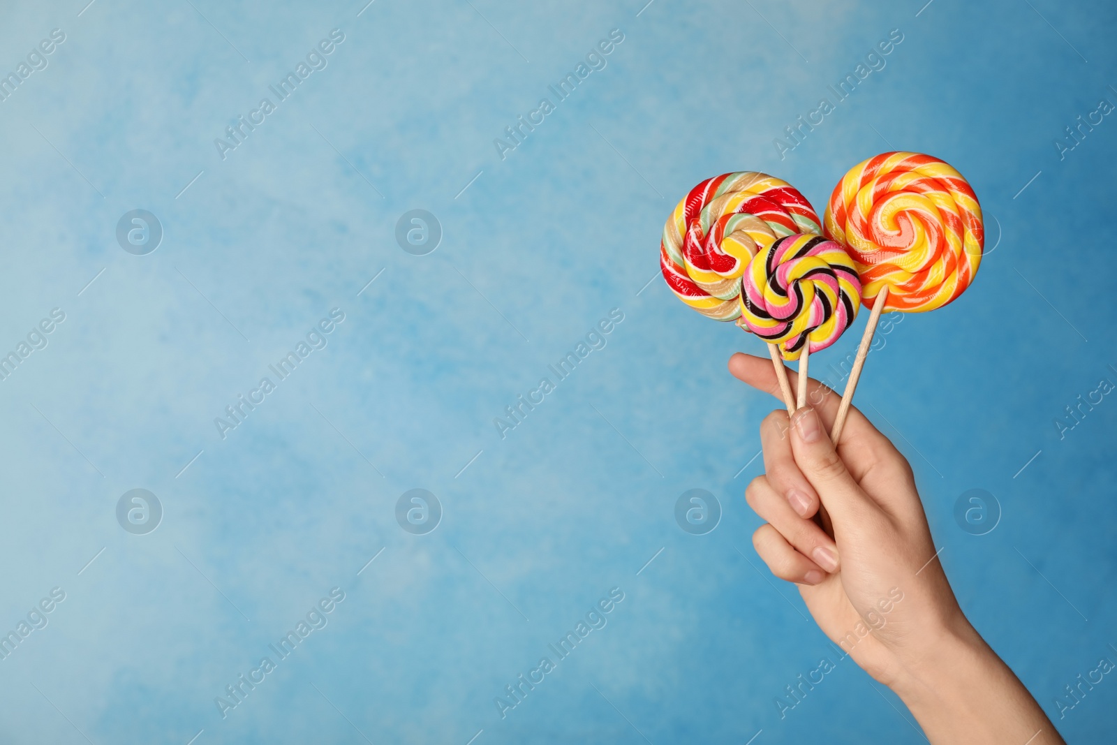 Photo of Woman holding yummy candies on color background. Space for text