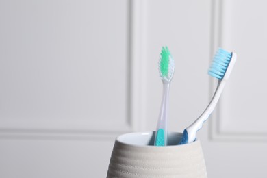 Photo of Plastic toothbrushes in holder near white wall closeup. Space for text