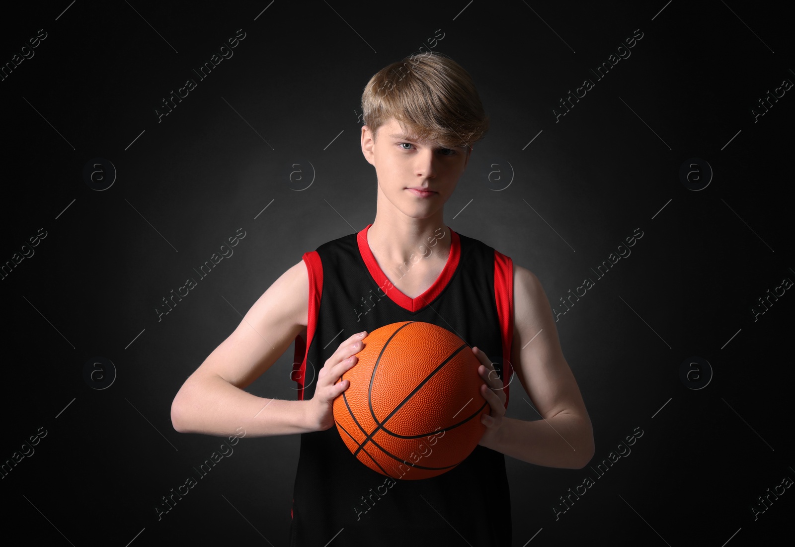 Photo of Teenage boy with basketball ball on black background