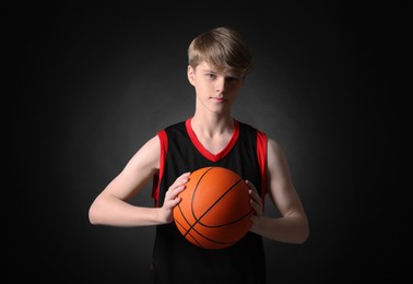 Photo of Teenage boy with basketball ball on black background