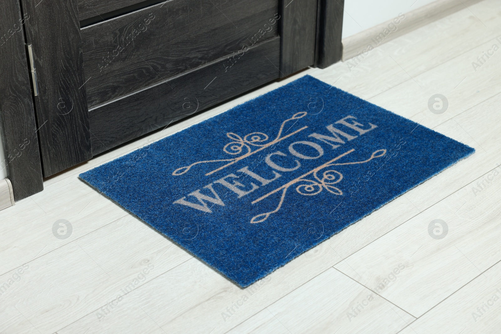 Photo of Blue doormat with word Welcome on white floor near entrance