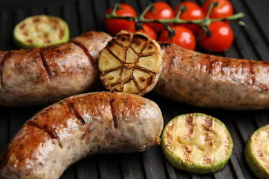 Photo of Cooking delicious fresh sausages with vegetables on modern grill, closeup