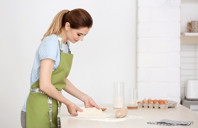 Photo of Woman preparing dough on table in kitchen