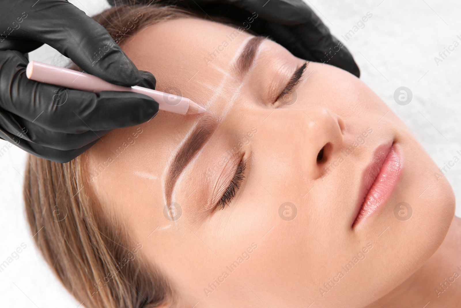 Photo of Young woman undergoing eyebrow correction procedure in salon