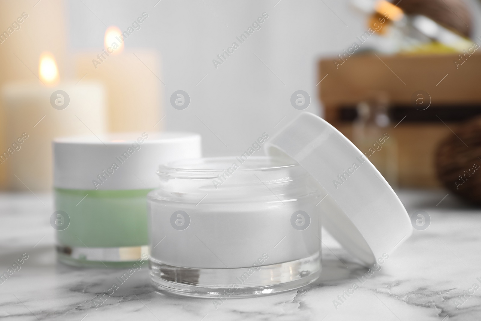 Photo of Jars of facial cream on white marble table