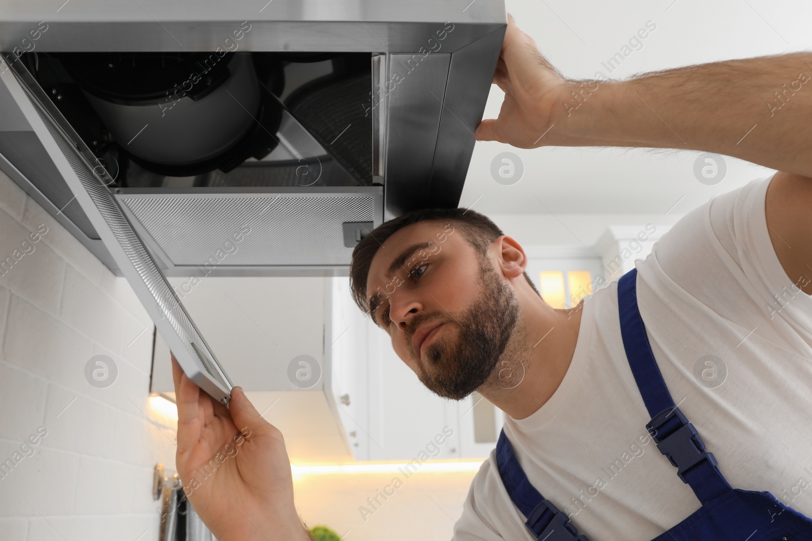 Photo of Worker repairing modern cooker hood in kitchen