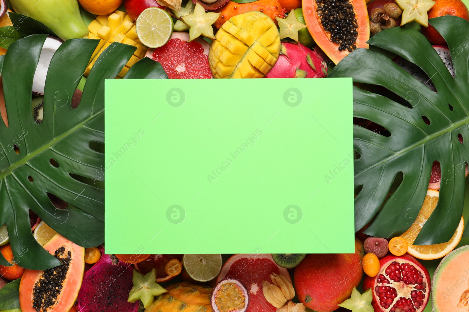 Photo of Different exotic fruits and blank card as background, top view. Space for text